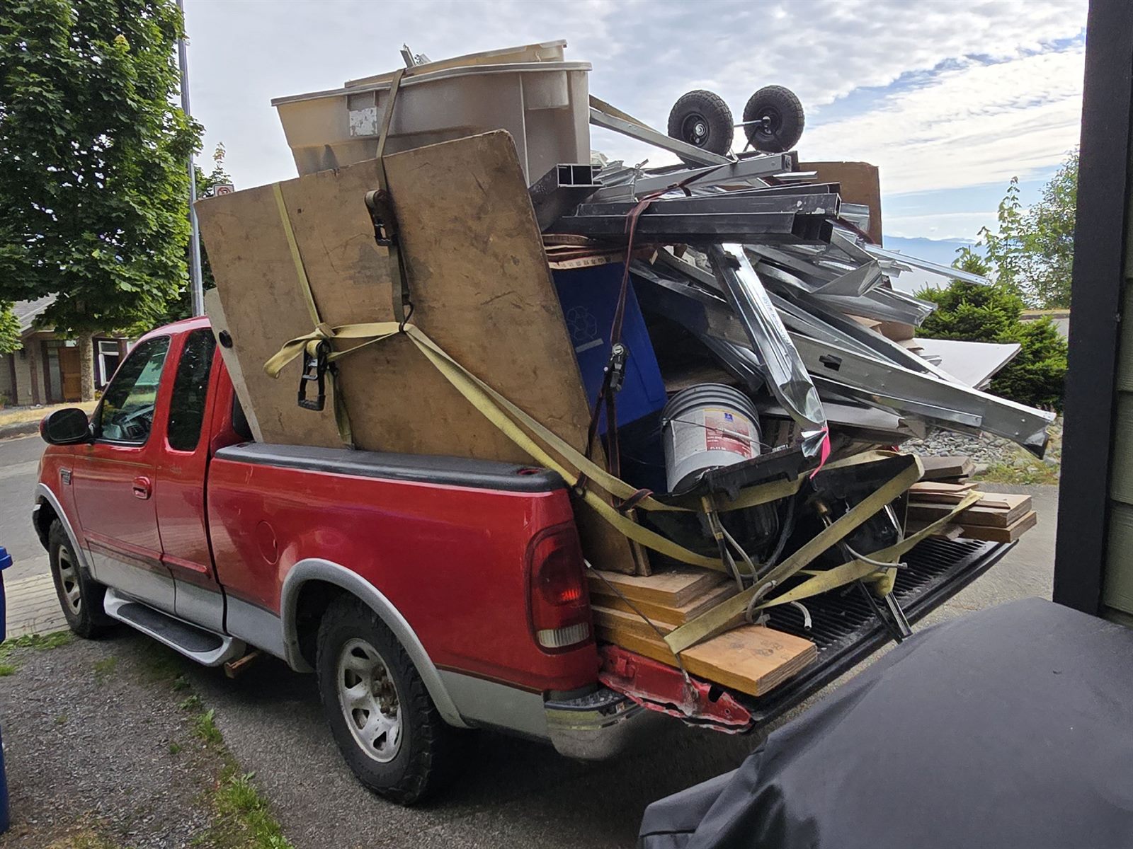 Loaded Nanaimo Junk Removal truck parked beside a home.